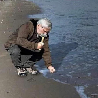 Guy Hammering Nails Into Sand